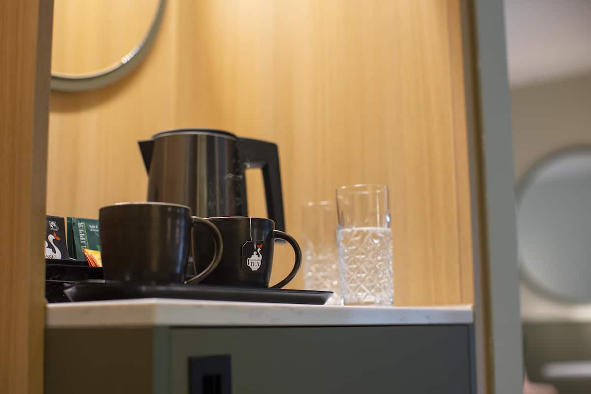 Un coin cuisine comprenant une machine à café, une tasse et un pichet en verre, le tout posé sur un plan de travail.