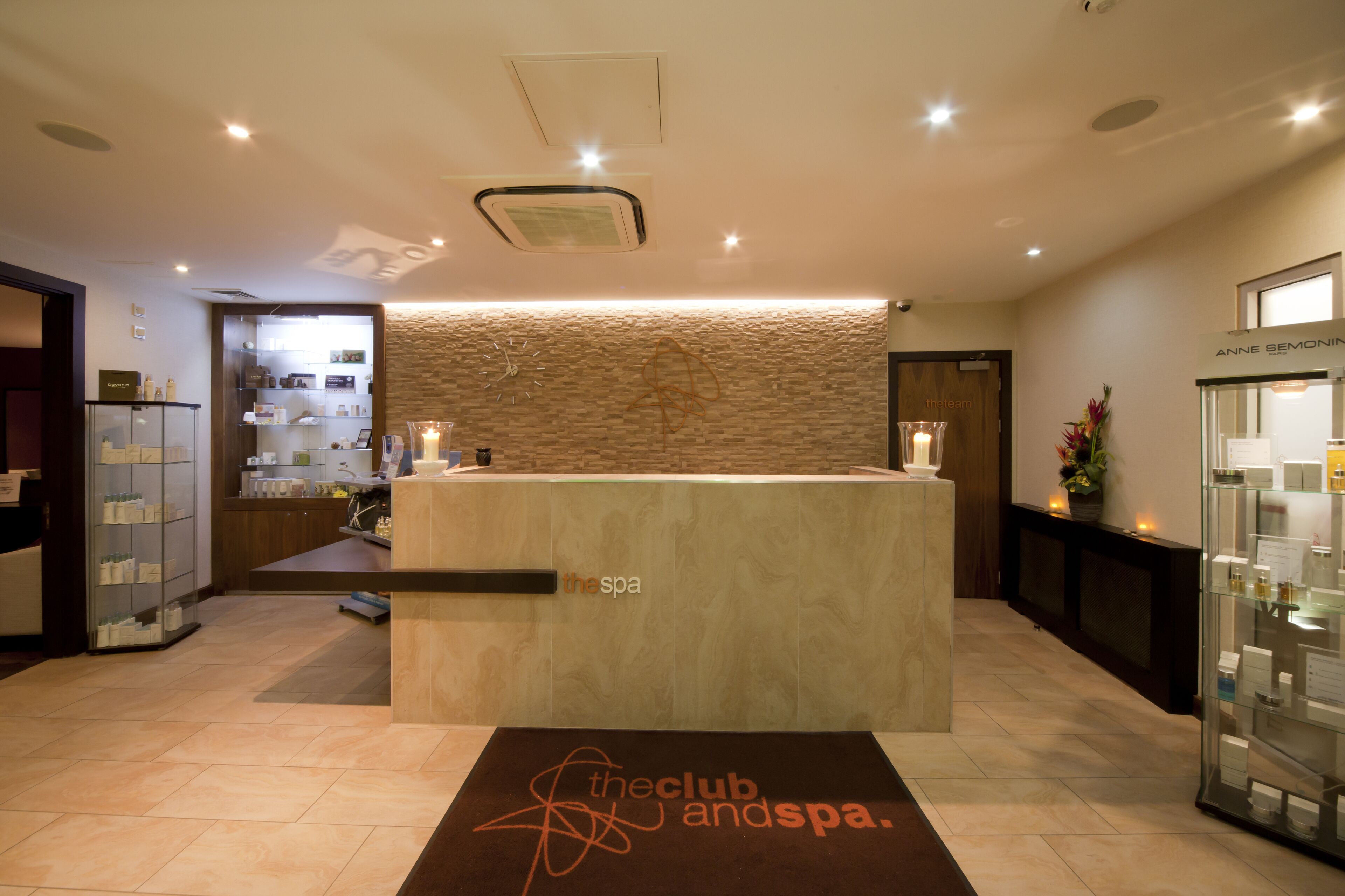 A reception area with a reception desk, a clock, a wall with a textured pattern, and a display case with items.