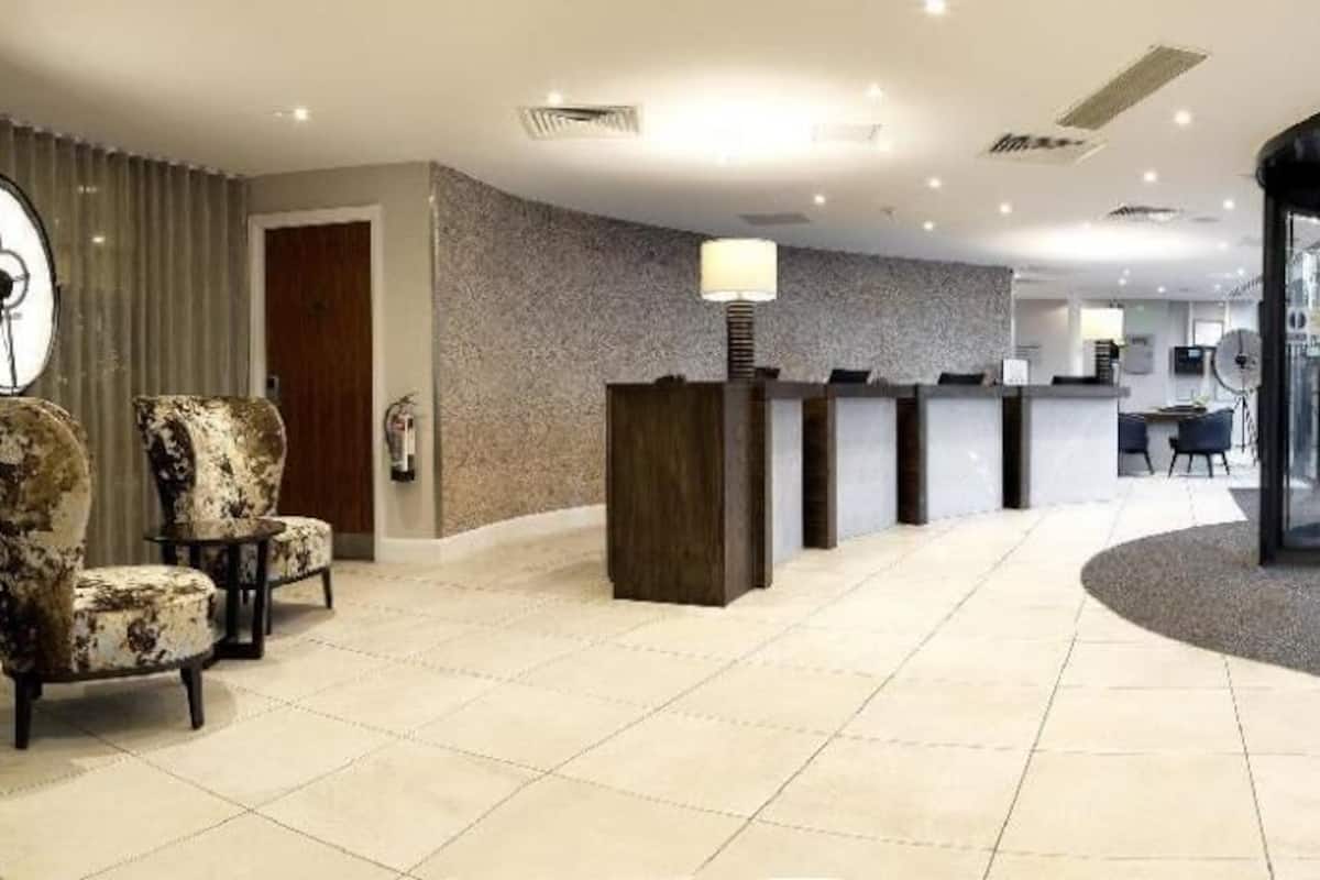Un hall d’hôtel comprenant un comptoir d’accueil, un espace salon et une porte tournante.