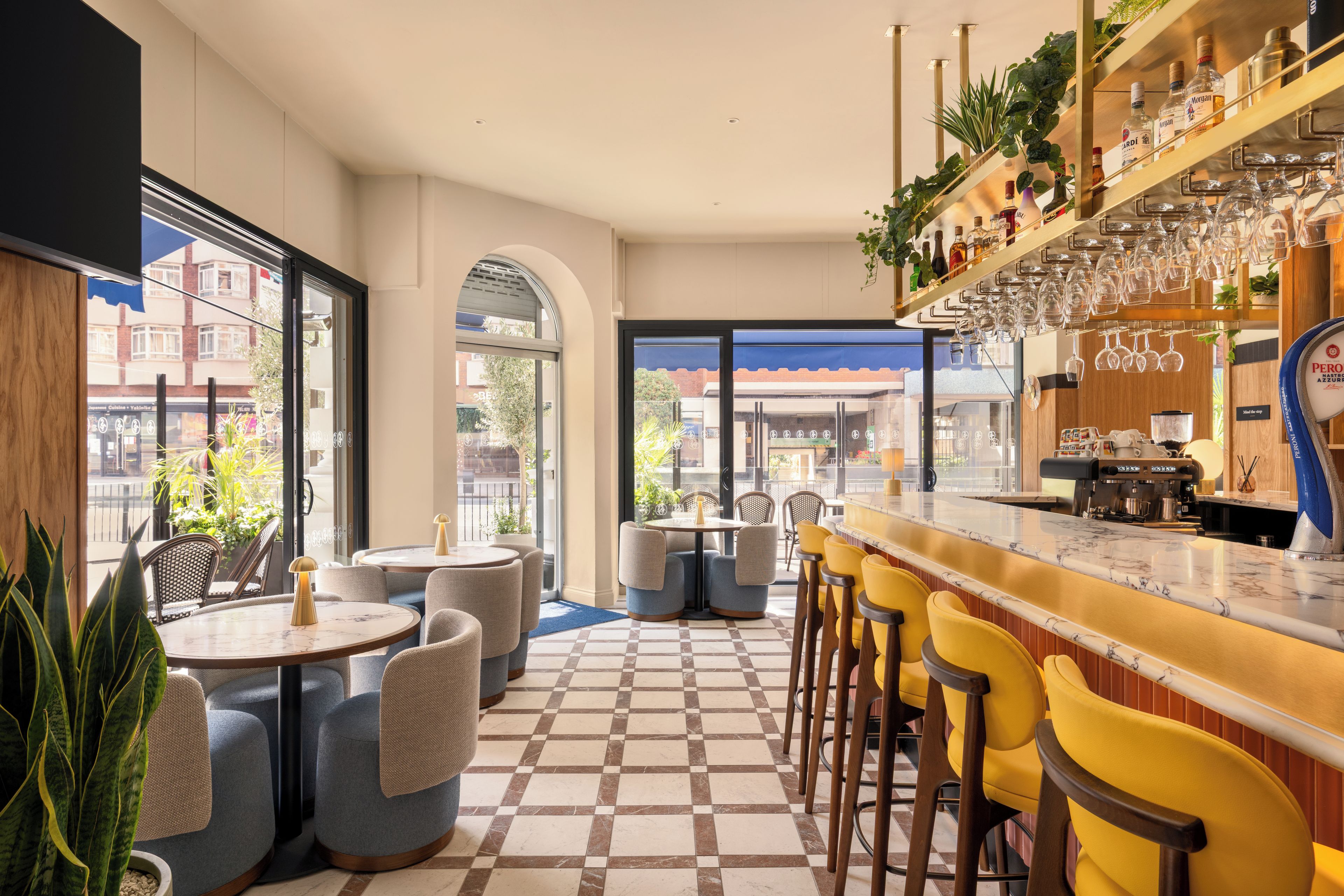 Una zona de bar con asientos, suelo a cuadros y vistas a la calle.