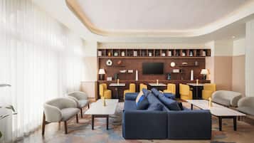 A modern living room with a sectional sofa, armchairs, a coffee table, and a flat-screen TV mounted on a wooden wall.