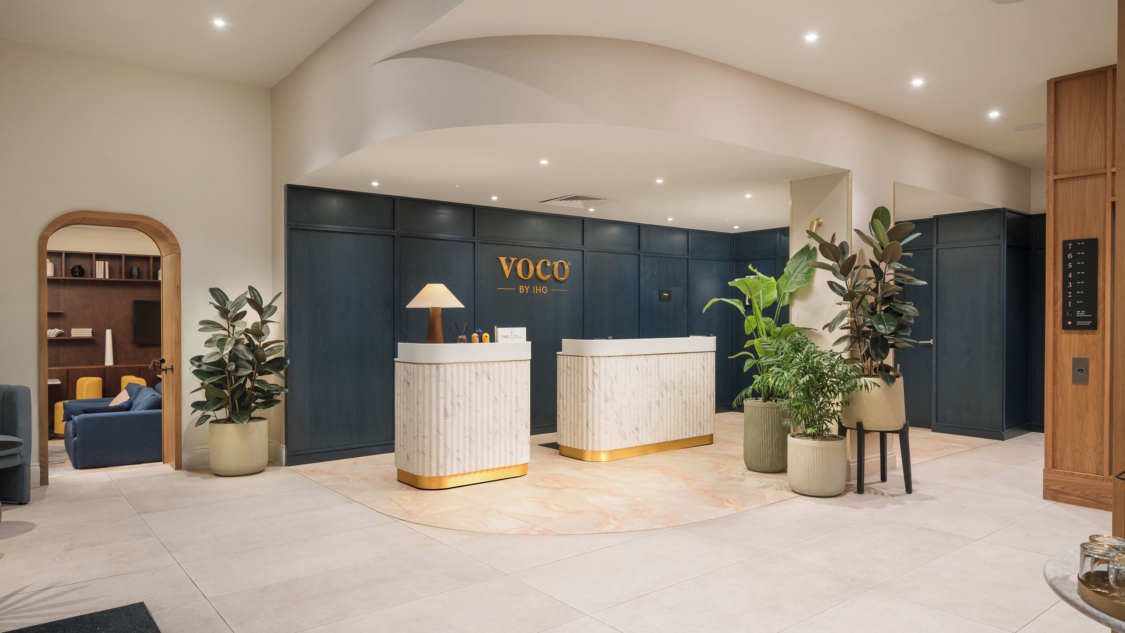A reception area with a reception desk, a seating area with a sofa and chairs, and a wooden bookshelf.