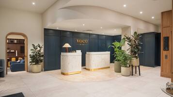 A reception area with a reception desk, a seating area with a sofa and chairs, and a wooden bookshelf.
