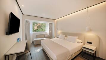 Una habitación de hotel moderna con una cama grande, un escritorio, un sofá y un televisor.