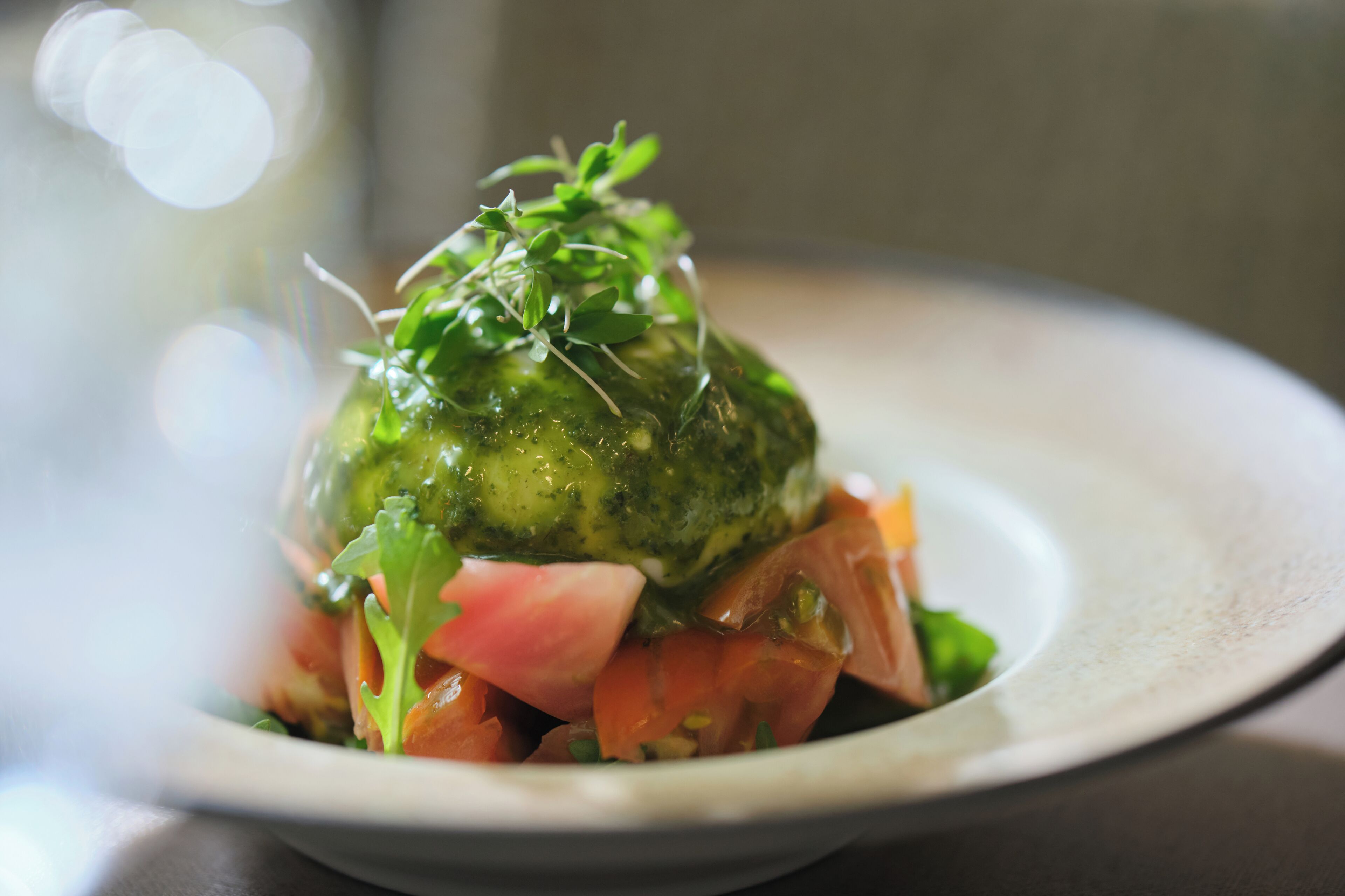 Un plat agrémenté d’une garniture verte, peut-être un légume ou une herbe aromatique, et accompagné de quelques feuilles vertes dans l’assiette.