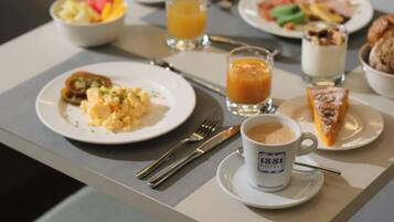 Una mesa de desayuno con platos de comida, una taza de café y un vaso de jugo de naranja.