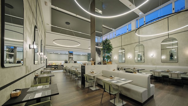 A modern restaurant with high ceilings, reflective surfaces, and a mix of seating options including tables and couches. - 1881 Madrid Ventas Hotel (Madrid)