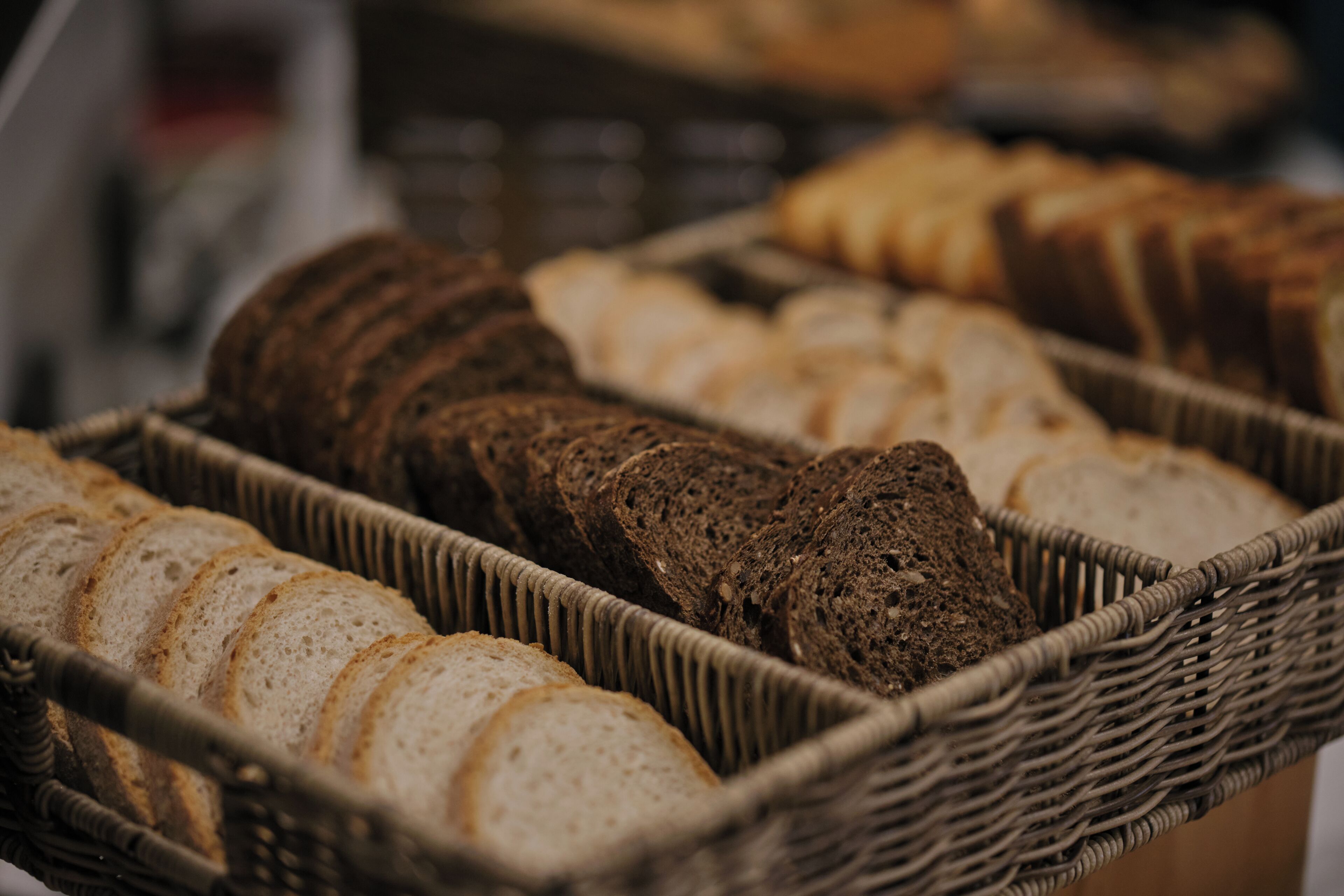 A variety of sliced breads in wicker baskets.