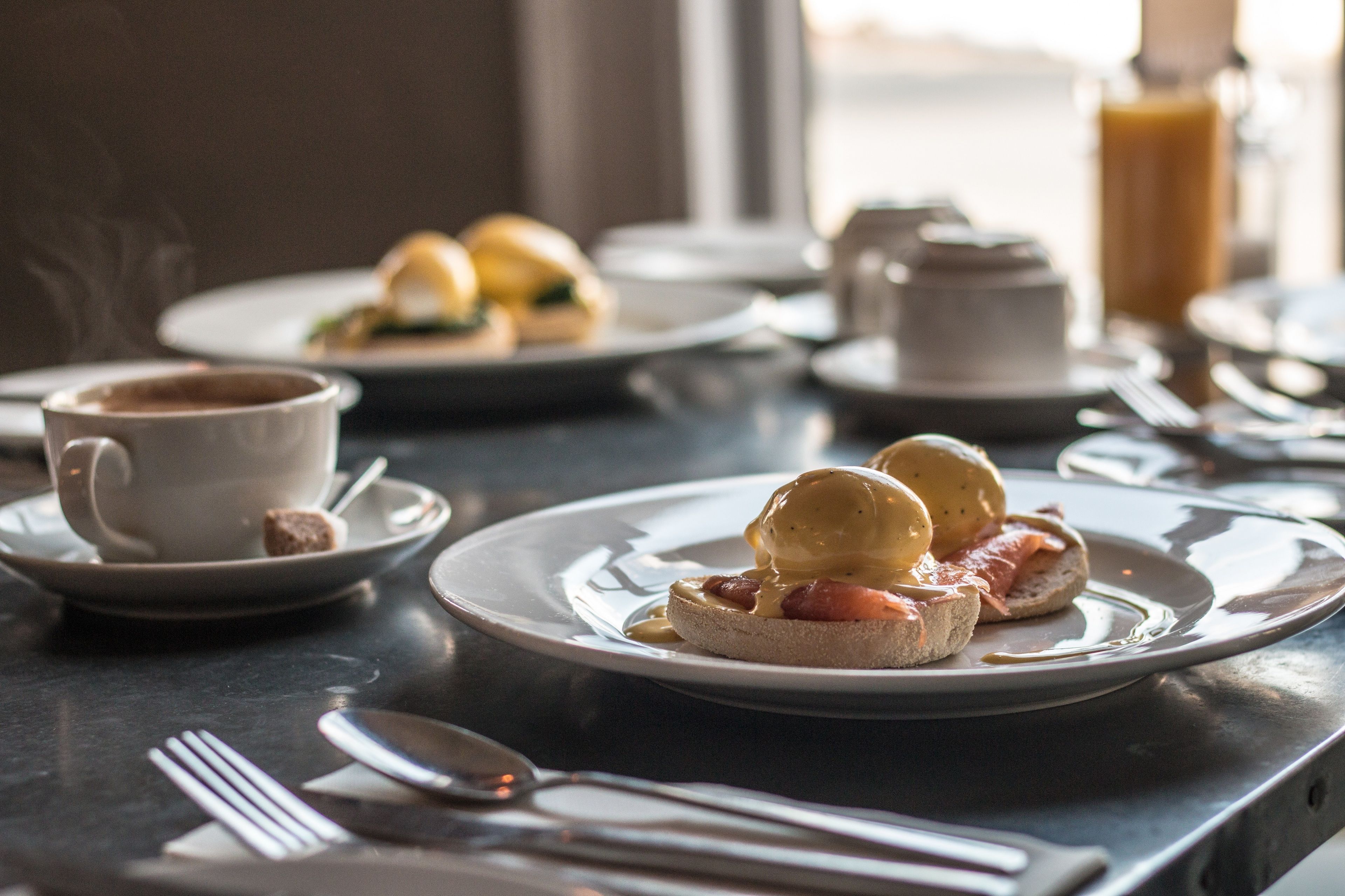 A breakfast setting with plates of food, a cup of coffee, and a bottle of orange juice on a table.