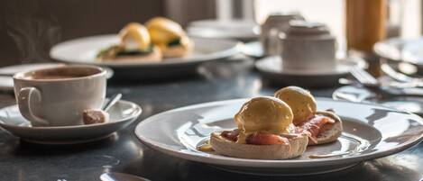 A breakfast setting with plates of food, a cup of coffee, and a bottle of orange juice on a table.