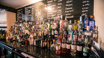 A bar with a variety of liquor bottles and a chalkboard menu listing drinks and prices.