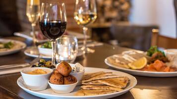 A dining table with various dishes, including flatbreads, olives, and a bowl of hummus.