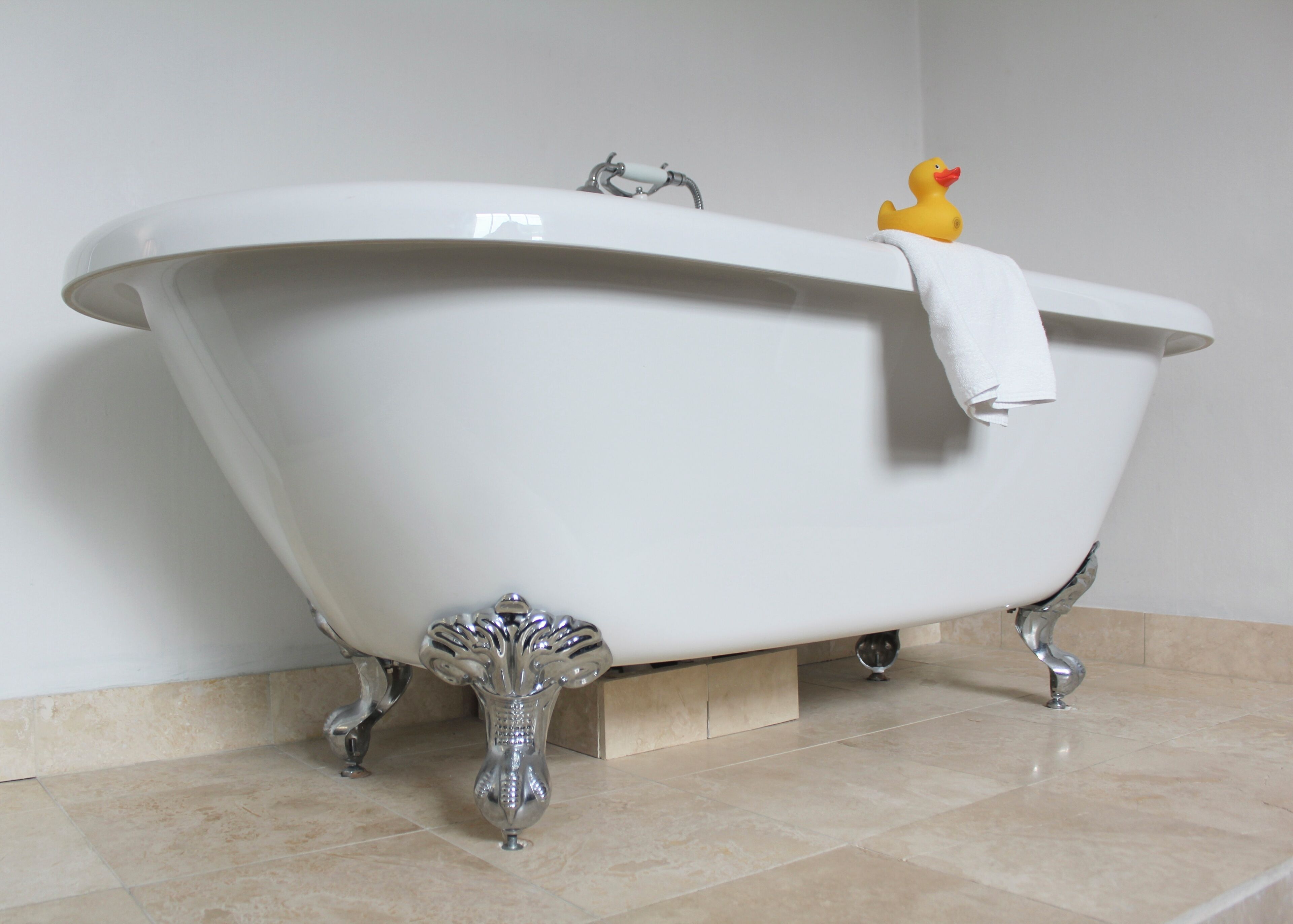 A white freestanding bathtub with a single faucet and a rubber duck toy on the edge.