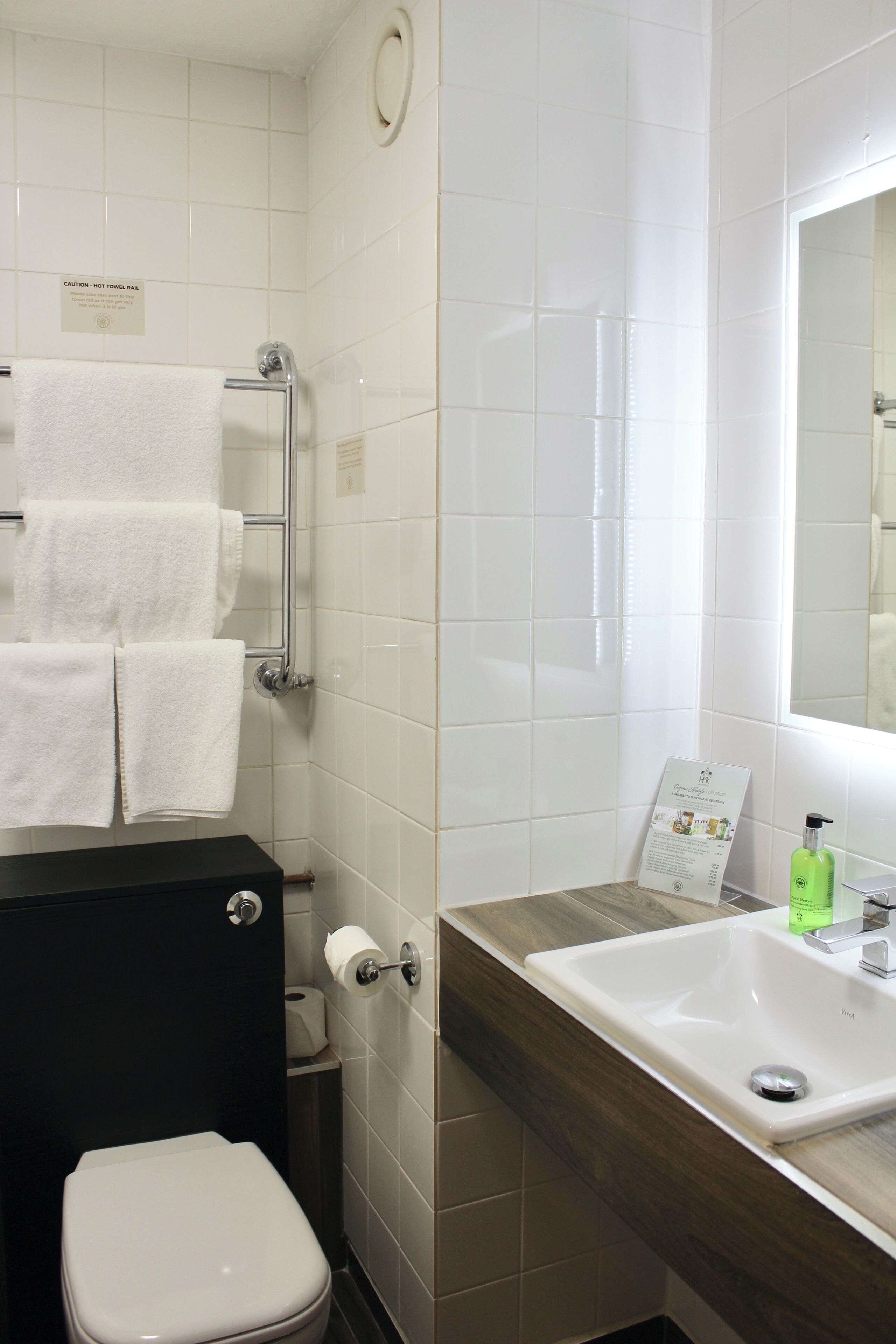 A bathroom with a toilet, a sink, and a towel rack with multiple towels.