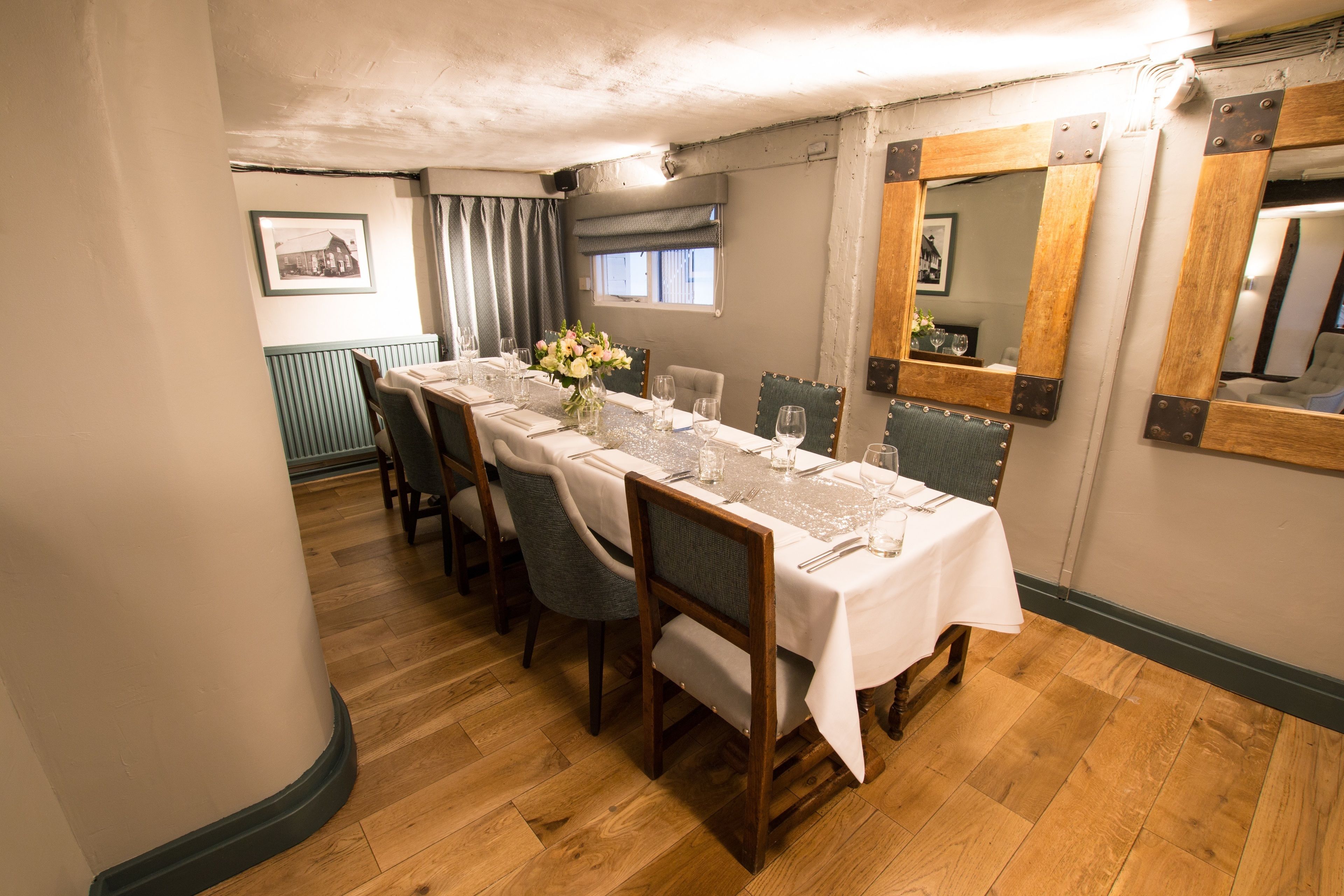 A dining room with a long table set for six, wooden chairs, and a mirror on the wall.
