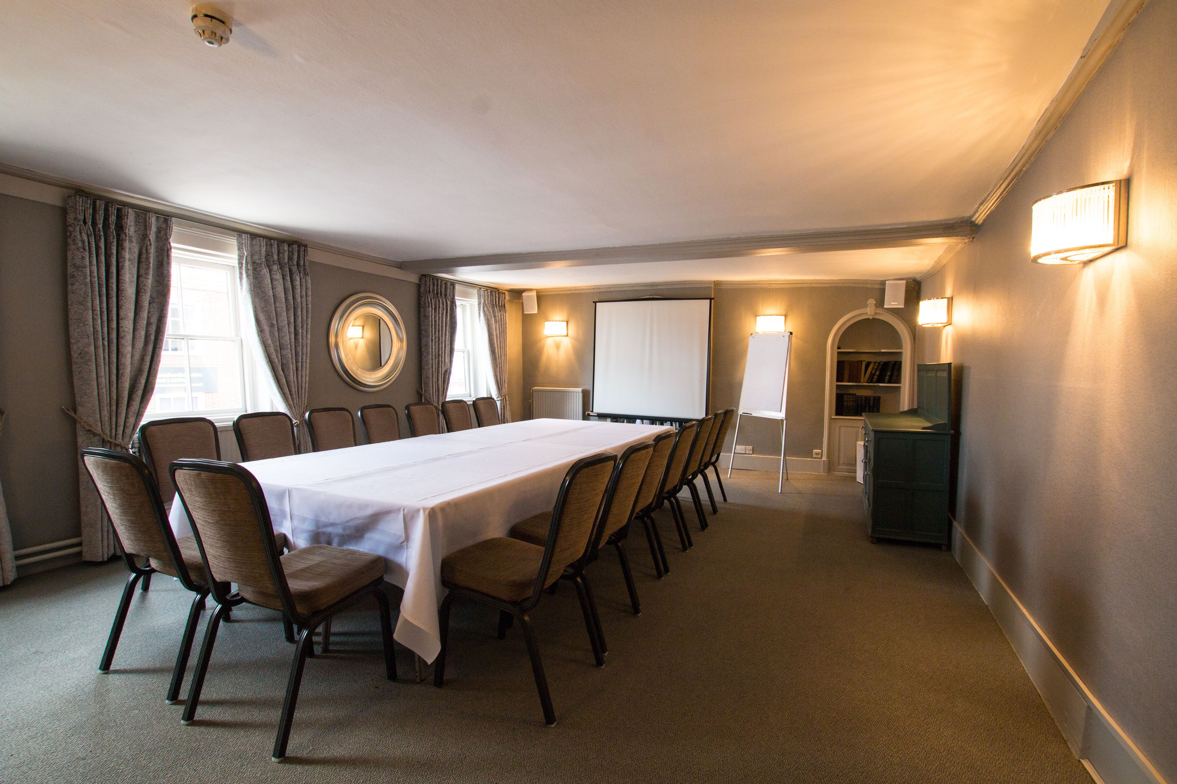 Une salle de conférence équipée d’une longue table, de chaises, d’un écran de projection et d’un tableau blanc.