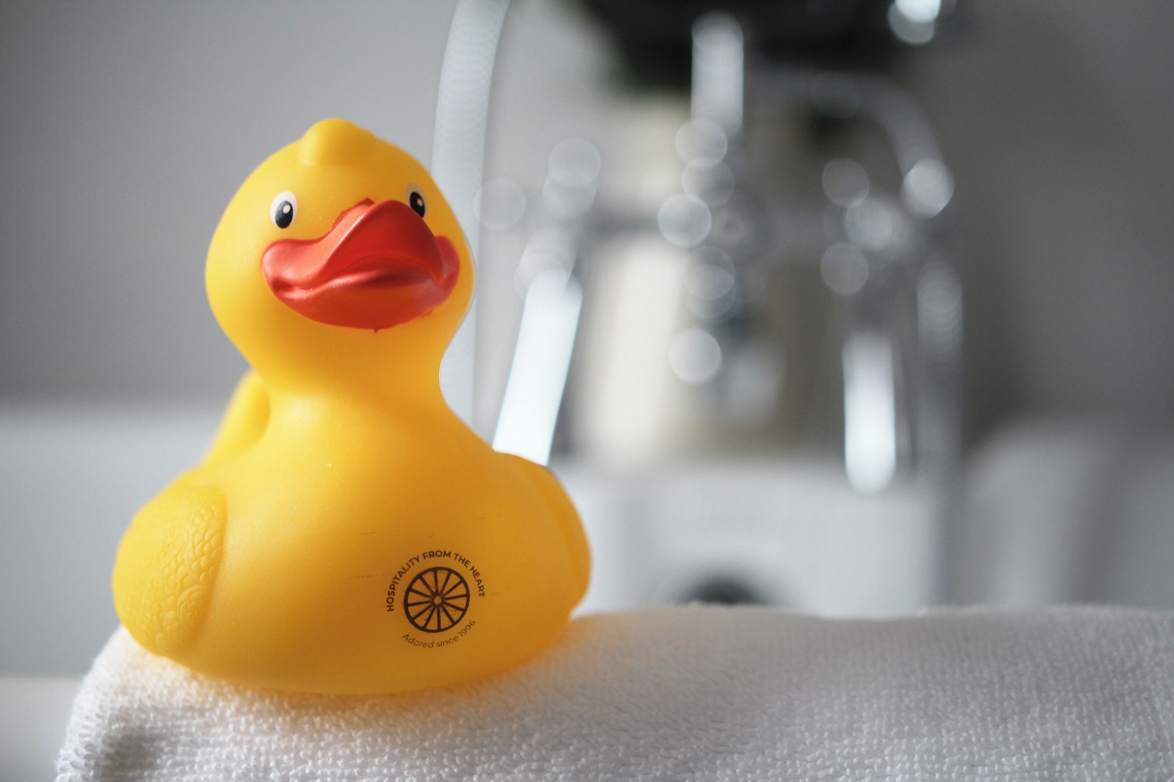 A yellow rubber duck on a white towel.
