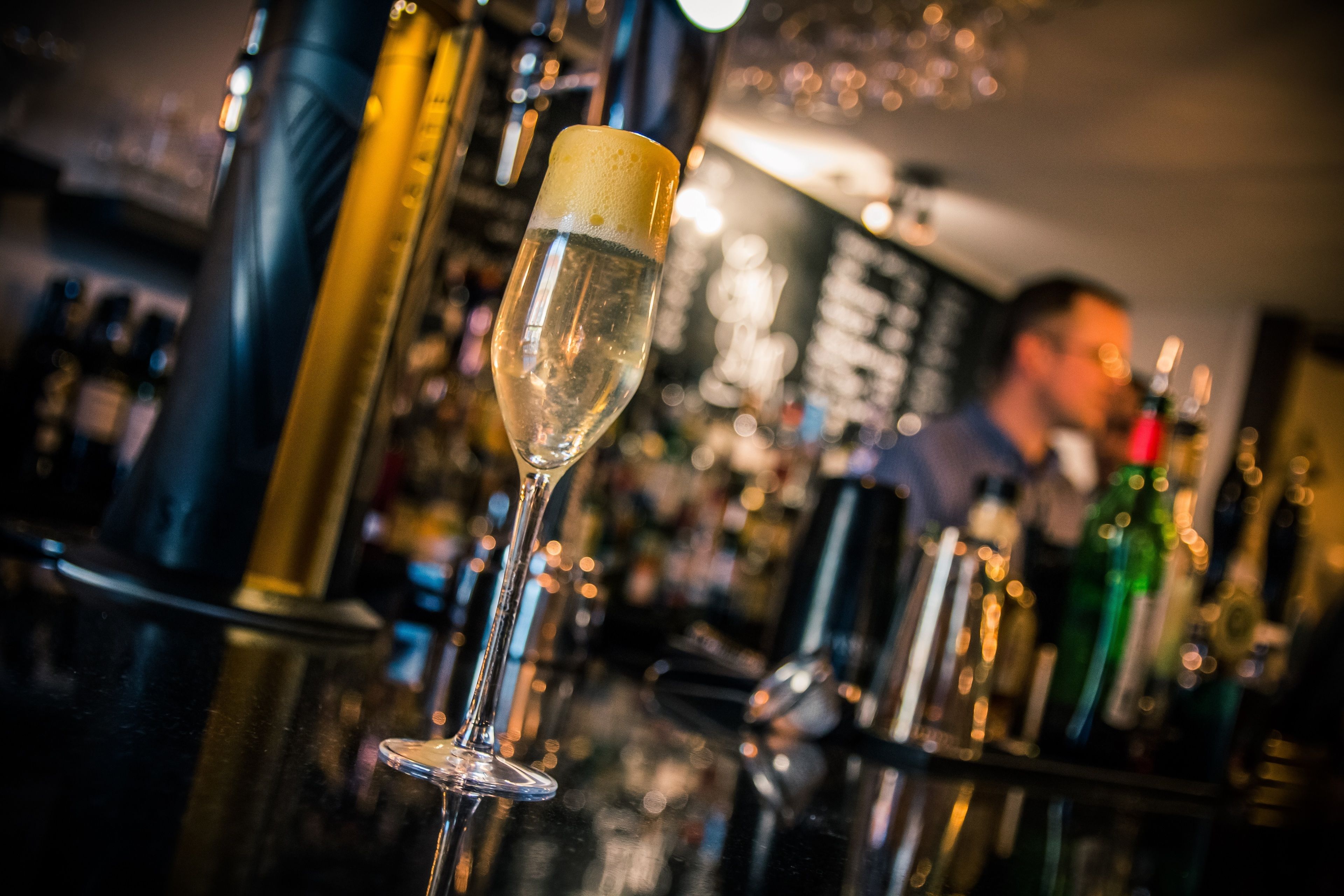 Un bar con una copa de champán y varias botellas al fondo.