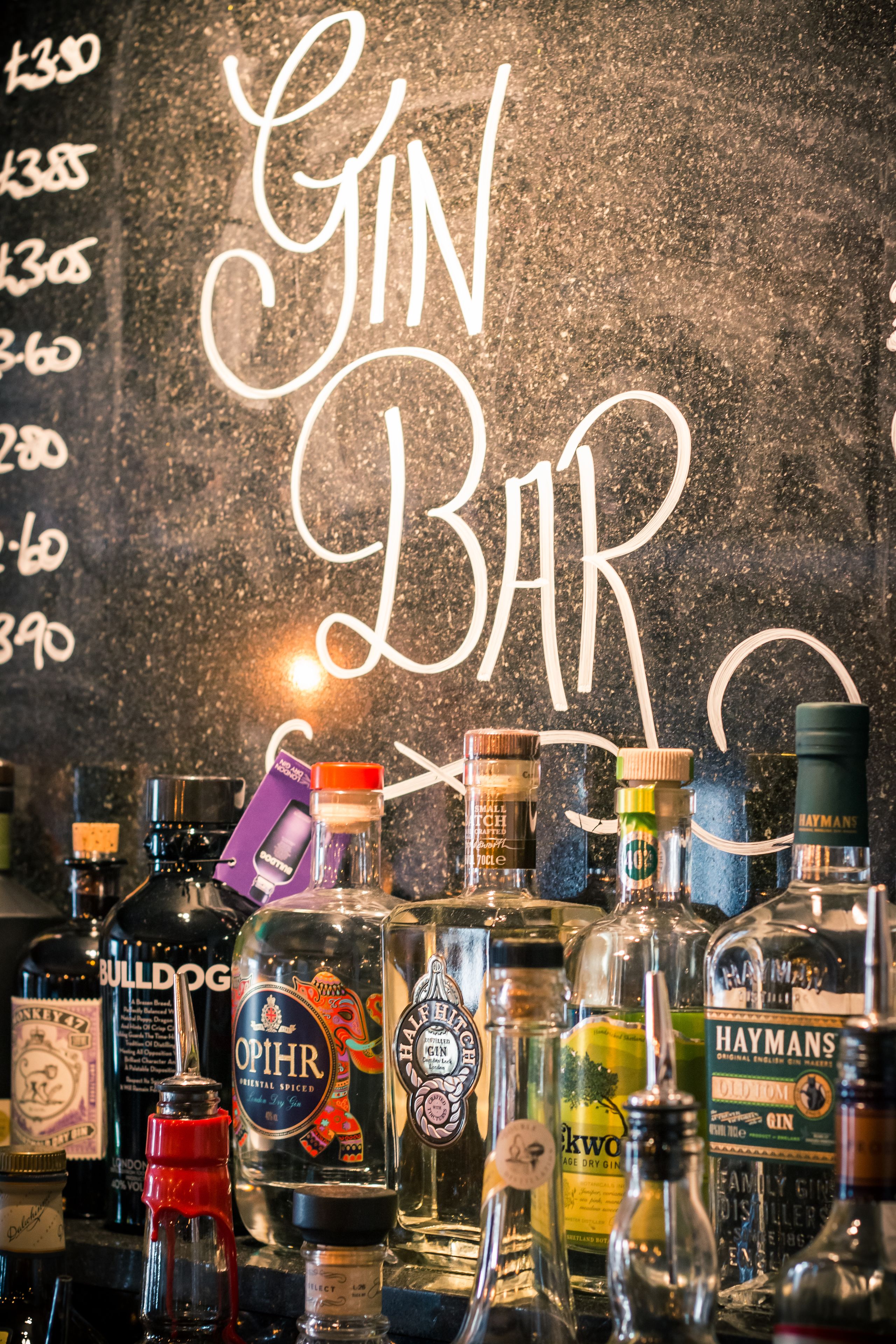 A bar with a sign reading "GIN BAR" and various bottles of alcohol on the counter.