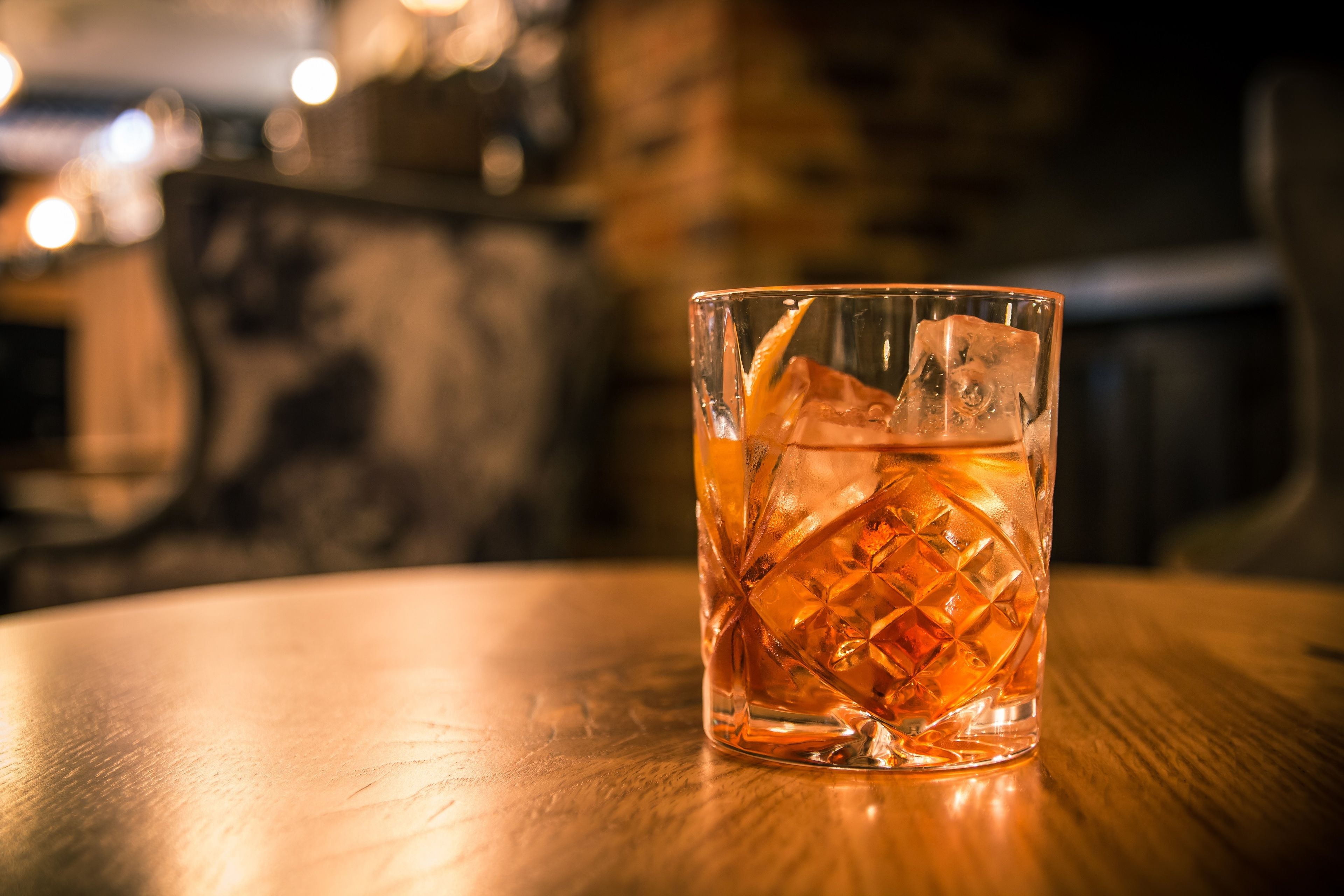 Un verre transparent contenant des glaçons, posé sur une surface en bois.