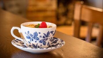 A white ceramic cup with blue floral patterns and a saucer on a wooden table.