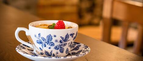 A white ceramic cup with blue floral patterns and a saucer on a wooden table.