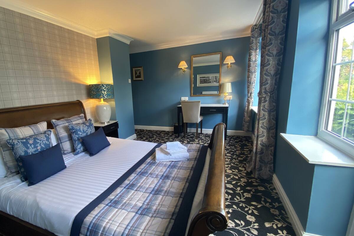 Quarto de hotel com uma cama grande, uma mesa e uma cadeira.