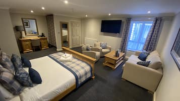 Una habitación de hotel con cama, sofá, escritorio y televisor.