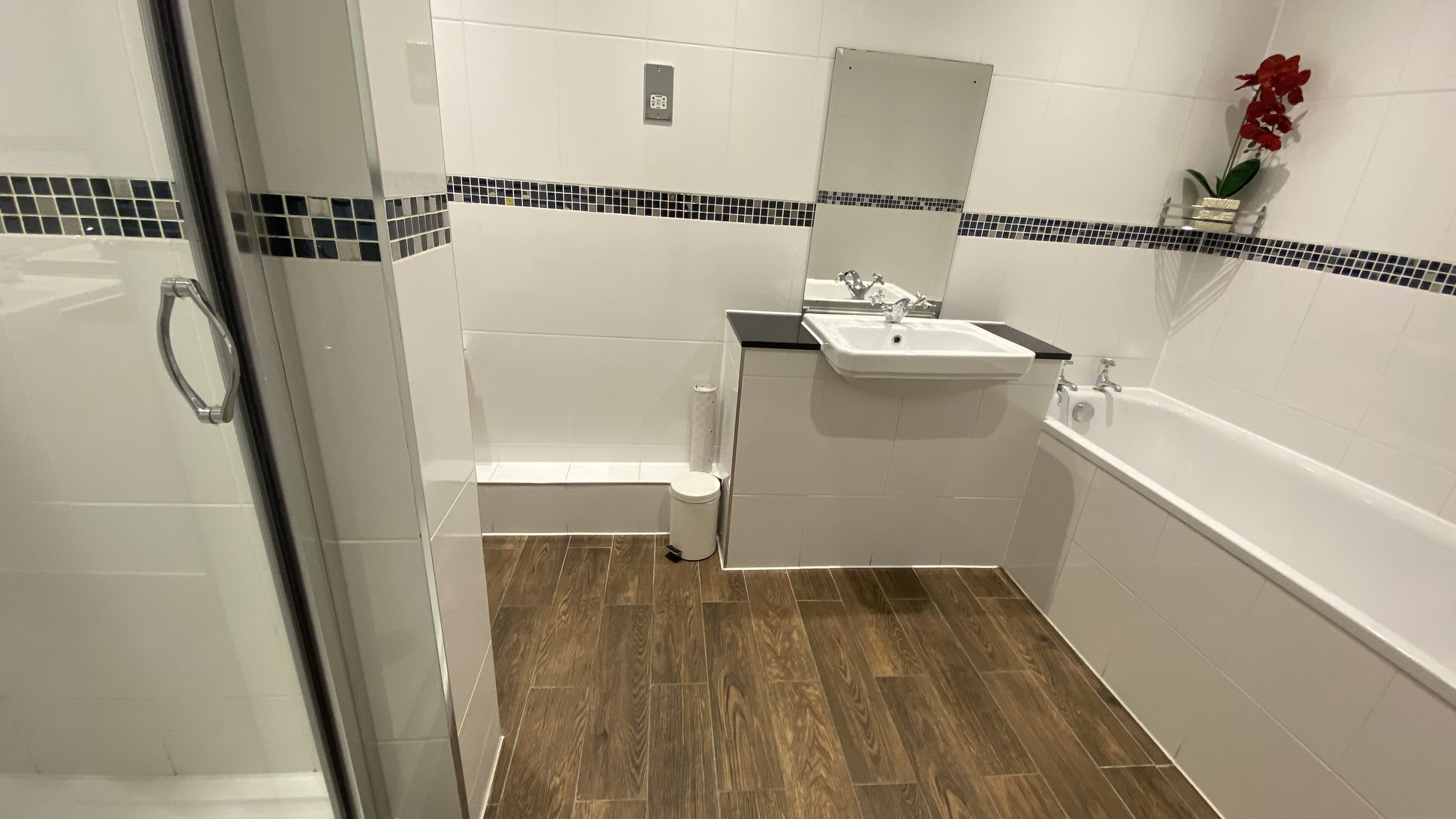Een badkamer met douche, toilet, wastafel en bad.