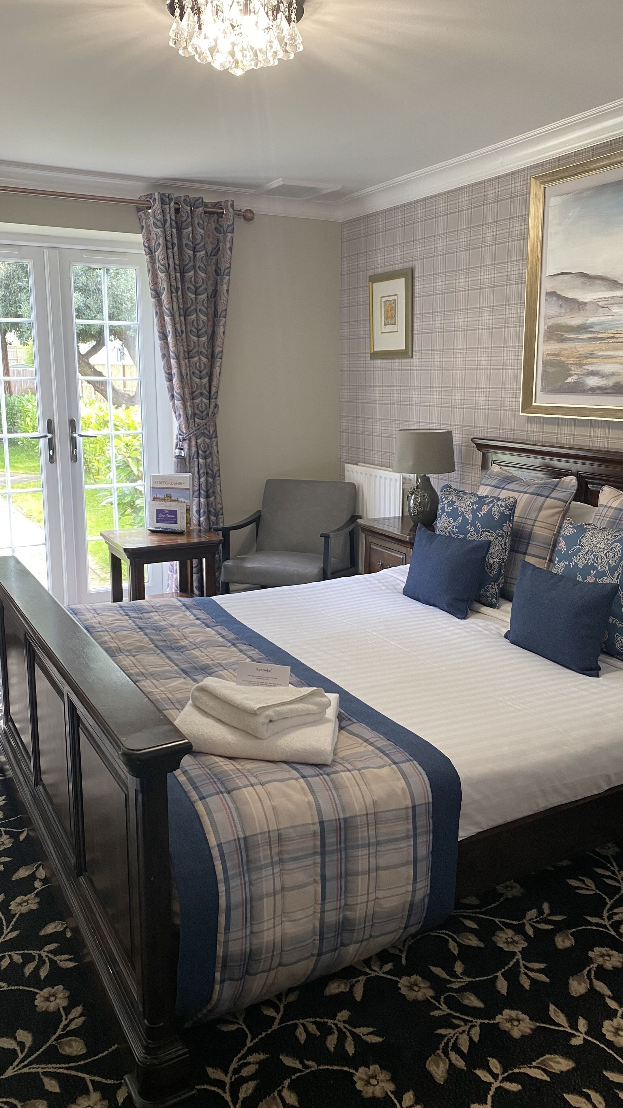 Een slaapkamer met een groot bed, een stoel, een tafel en een kroonluchter.