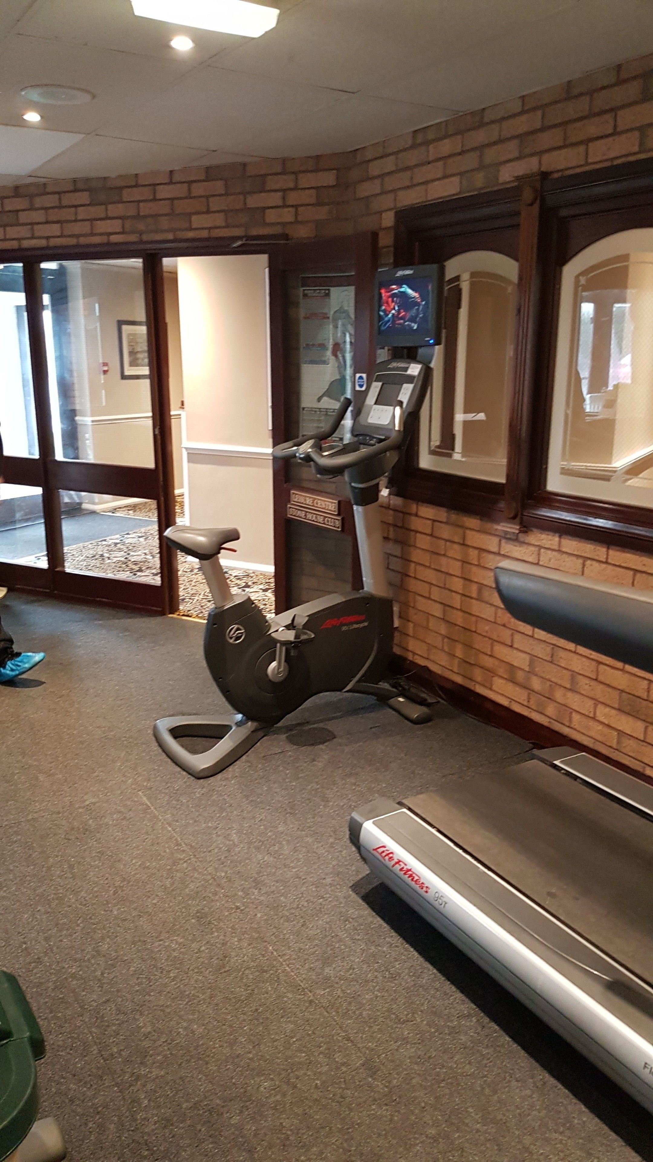 A gym with a treadmill, an elliptical machine, and a television screen.