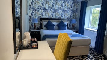 A hotel room with a bed, bedside tables, a desk, and a window with curtains.