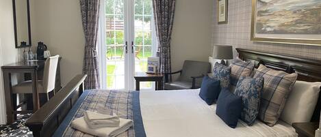 A hotel room with a bed, a desk, a chair, a lamp, and a painting on the wall.