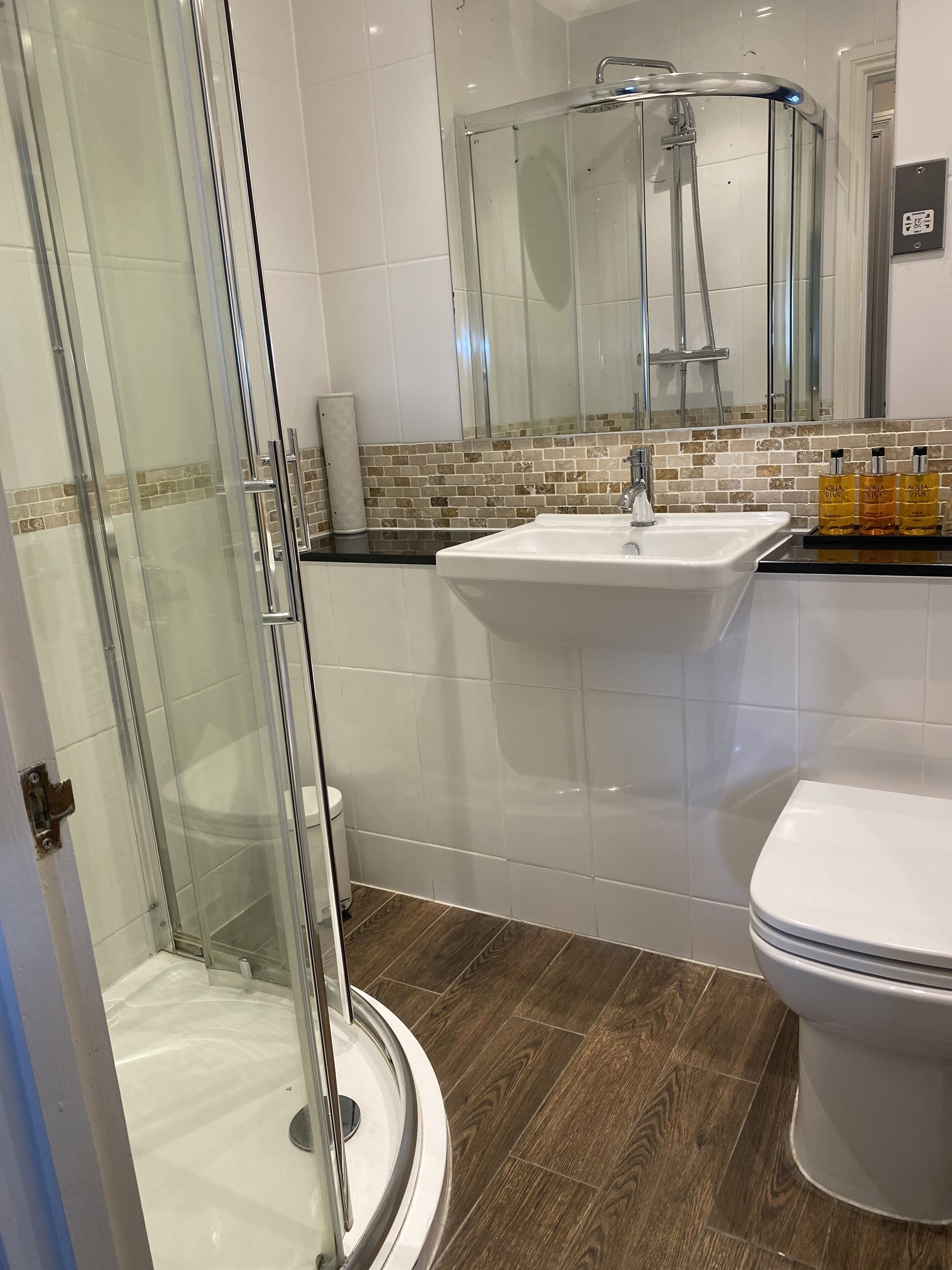 A modern bathroom with a glass-enclosed shower, a white sink, and a toilet.