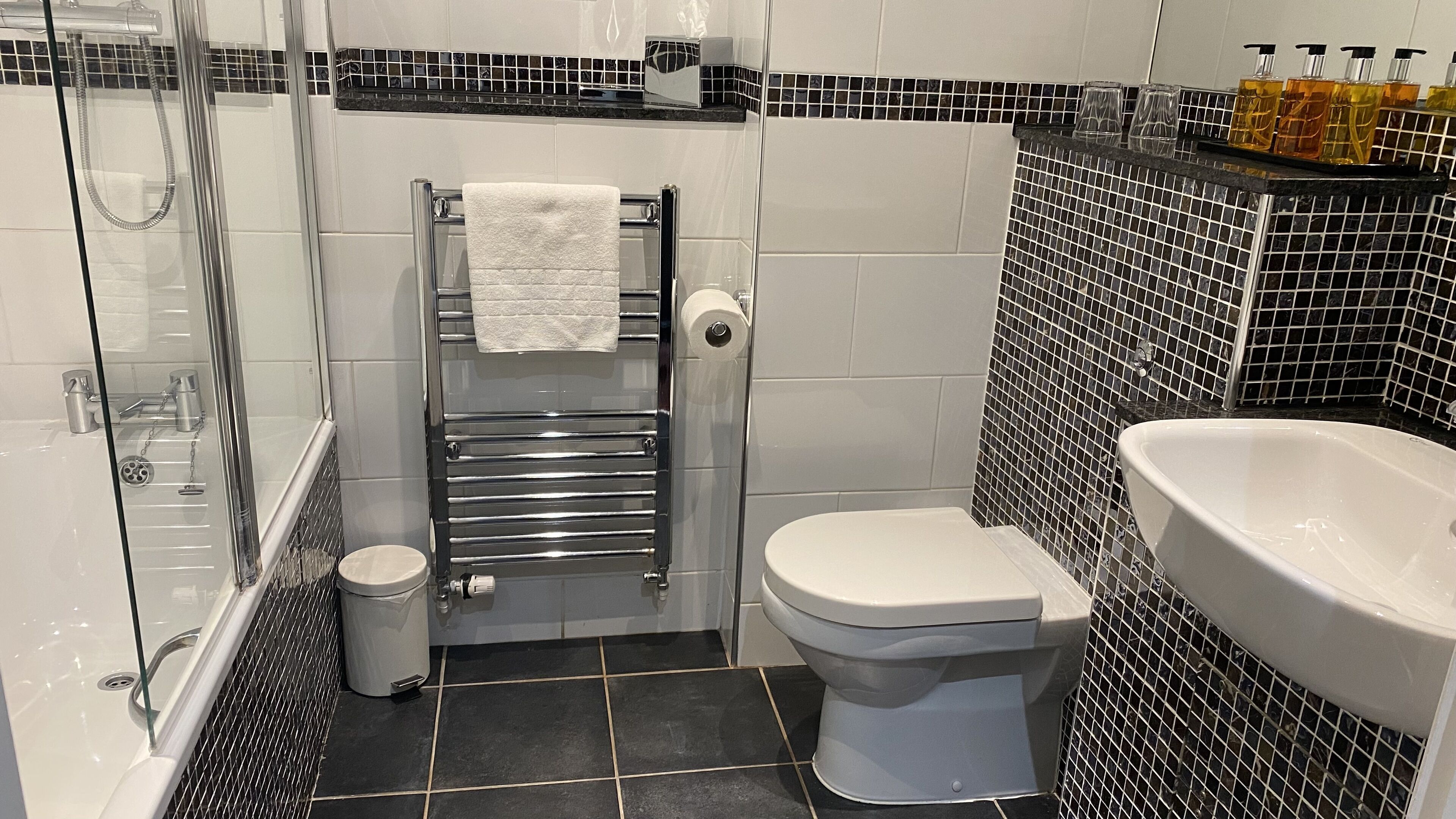 A bathroom with a glass-enclosed shower, a toilet, and a sink.