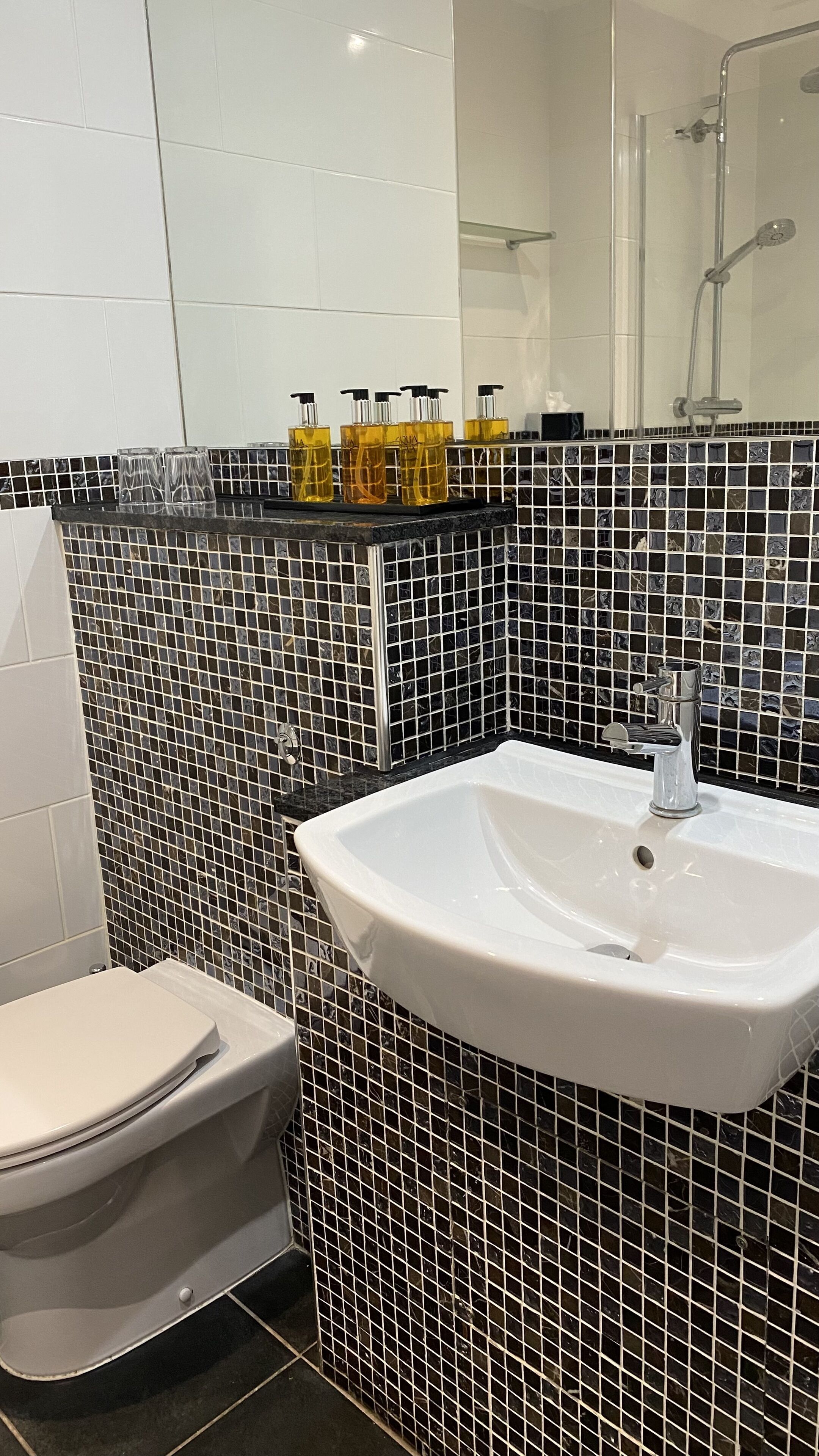 Ein Badezimmer mit einem weißen Waschbecken, einer Toilette und einer Dusche.