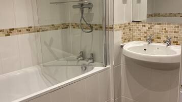 A modern bathroom with a glass-enclosed shower, a white sink, and a wooden floor.