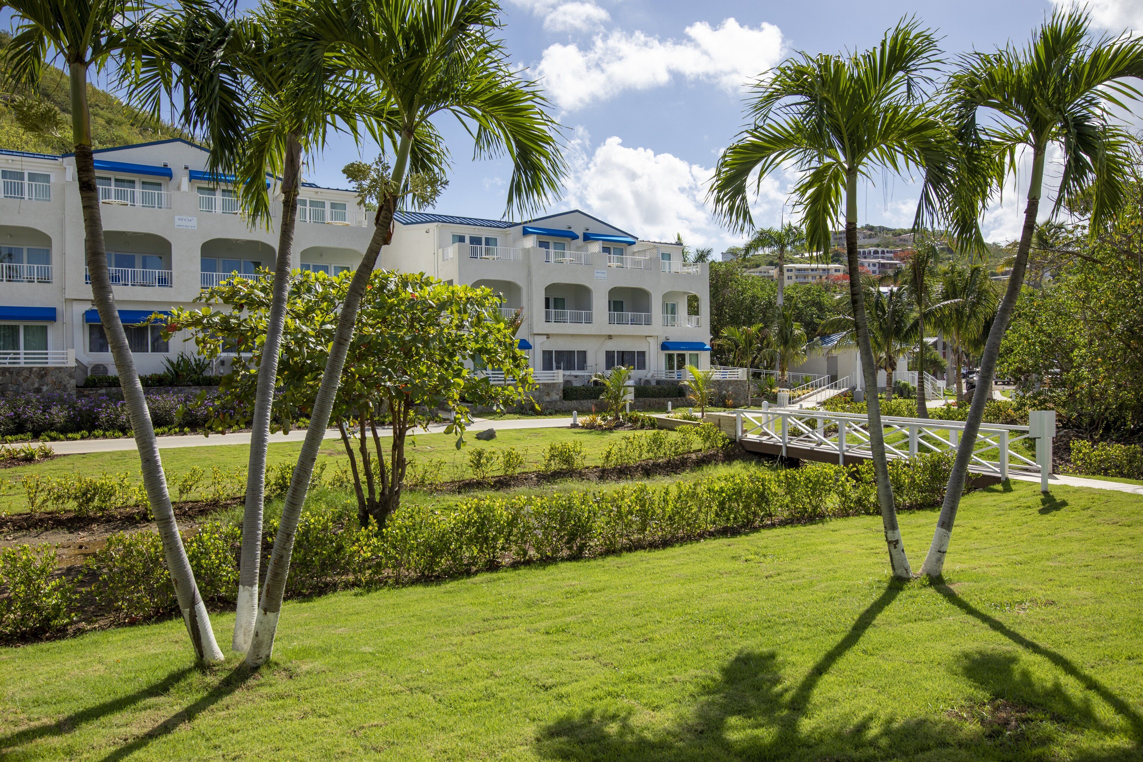 A hotel with multiple balconies, a well-maintained lawn, and a bridge.