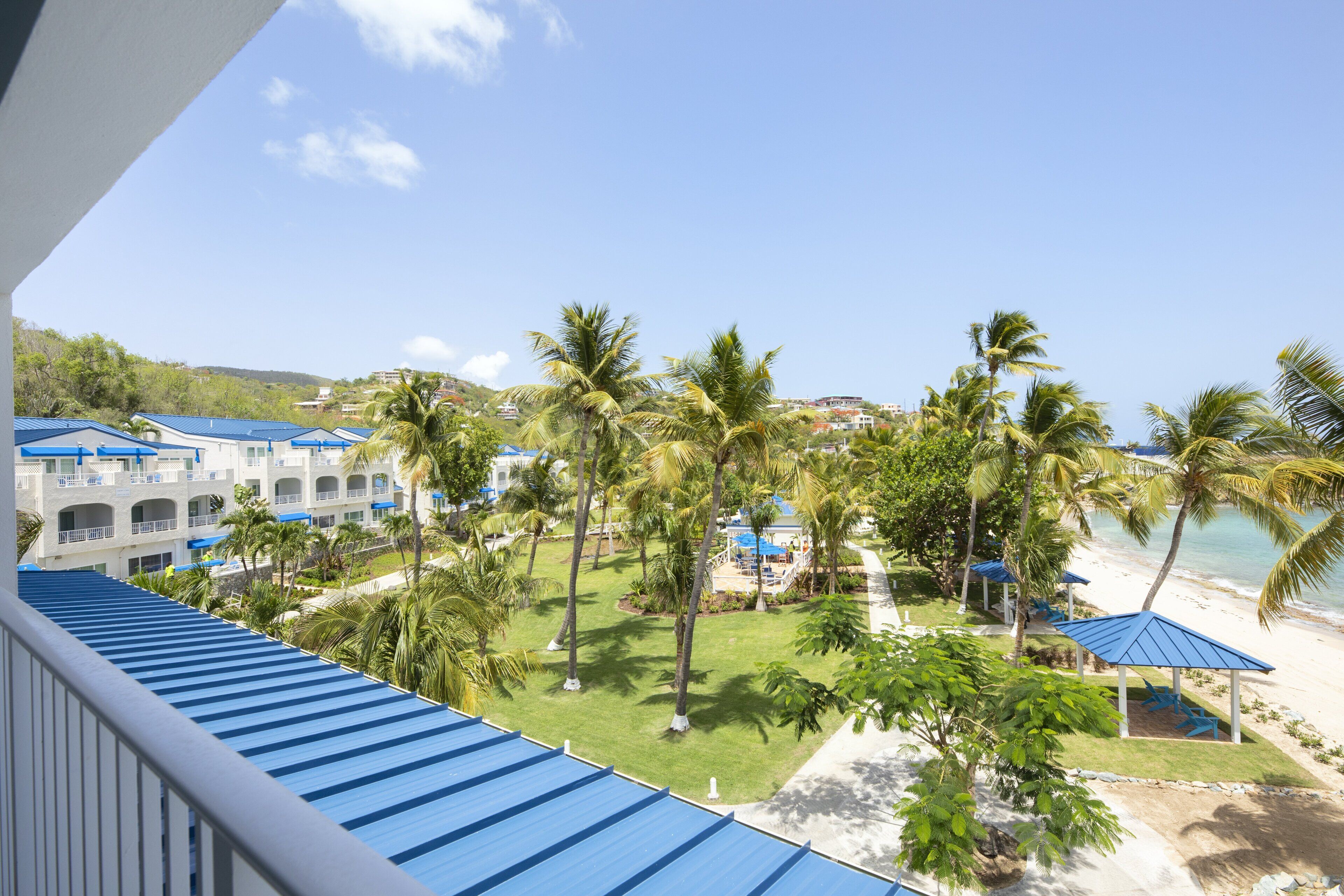 A resort with a pool area, palm trees, and a beach view.