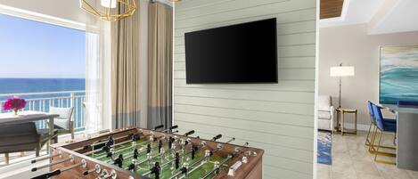 A room with a foosball table, a flat-screen TV, and a view of the ocean.