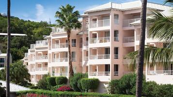 A multi-story hotel with balconies, surrounded by lush greenery and flowering plants.