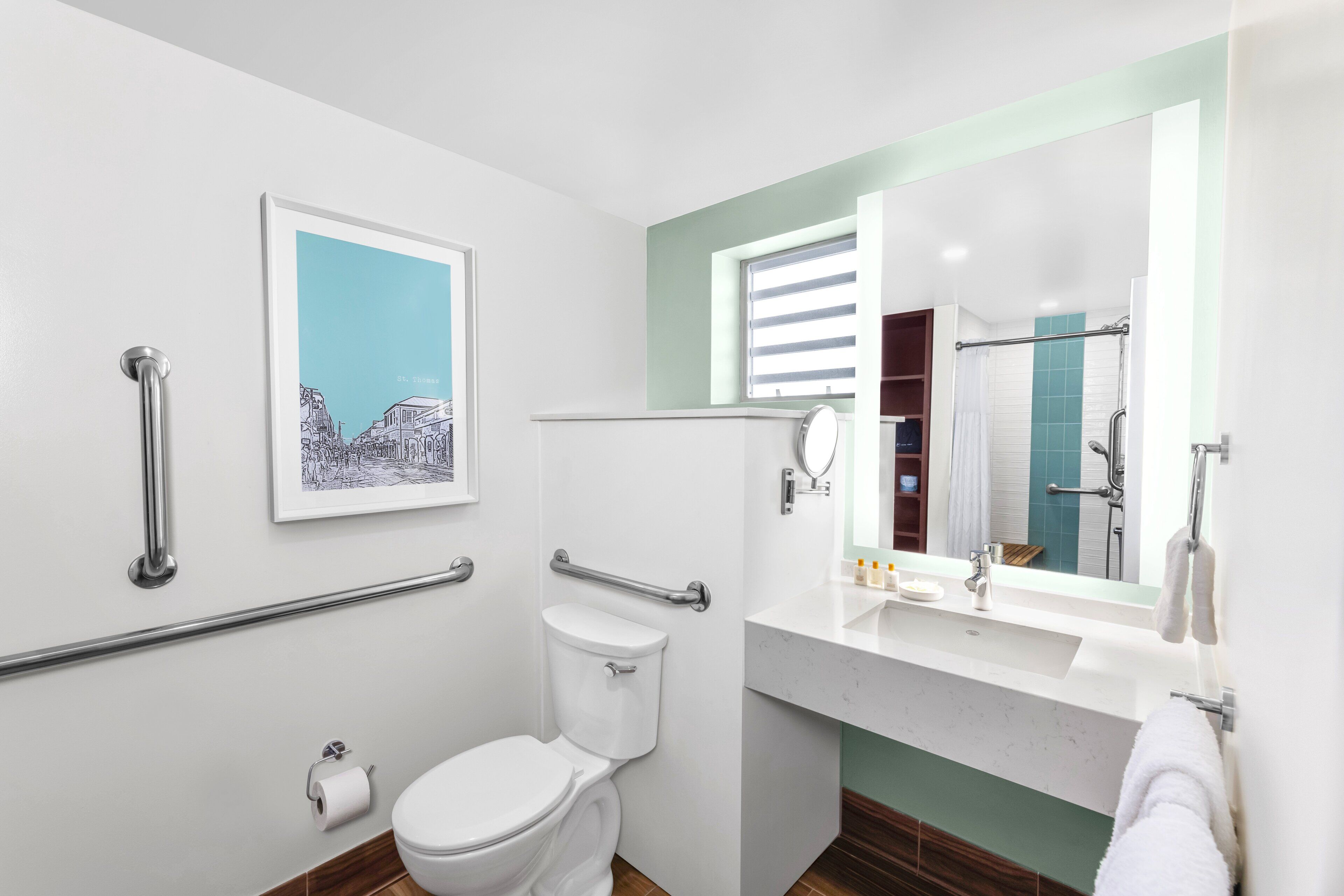 A modern bathroom with a toilet, handrails, a sink, and a mirror.