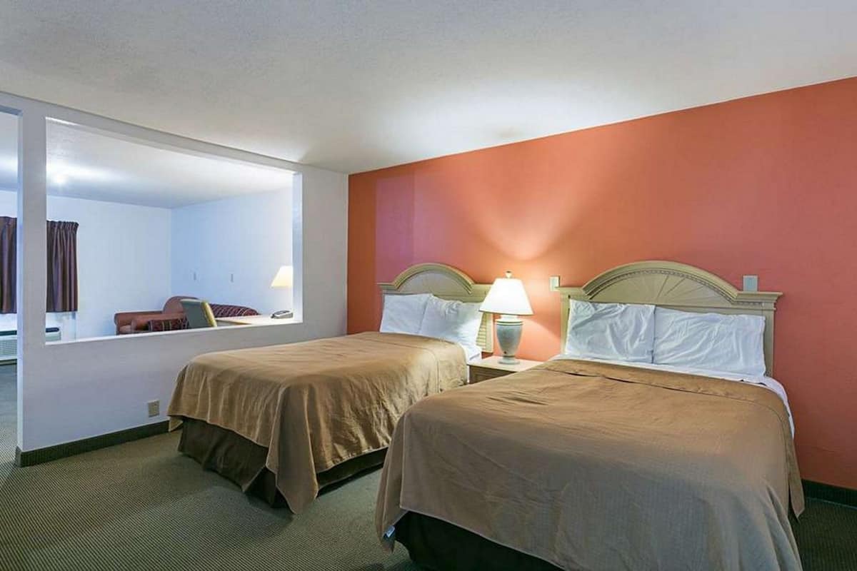 Habitación de hotel con dos camas, un espejo grande y vistas al exterior.