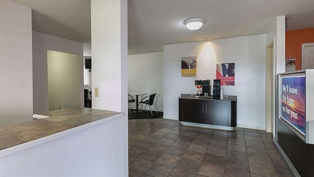 A modern kitchen with a dark countertop and a small dining area with a table and chairs. - Rodeway Inn & Suites Enterprise (Enterprise)