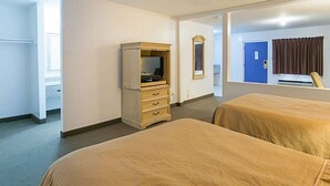 A hotel room with two beds, a dresser, a television, and a mirror. - Rodeway Inn & Suites Enterprise (Enterprise)