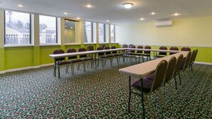 A conference room with a long table and chairs, large windows, and patterned carpet. - Rodeway Inn & Suites Enterprise (Enterprise)