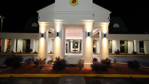A hotel entrance with a sign reading "Super 8 by Wyndham" and a covered entrance with columns. - Super 8 by Wyndham Florence SC I-95 North / Hwy 76 (Florence)