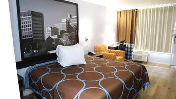 Una habitación de hotel con una cama grande, un televisor en la pared, un escritorio con una silla y una ventana con cortinas.