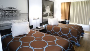 A hotel room with two beds, a nightstand, a desk, and a large framed picture on the wall. - Super 8 by Wyndham Florence SC I-95 North / Hwy 76 (Florence)