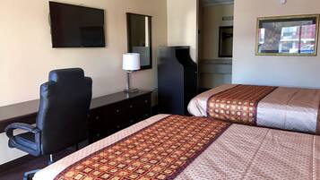 Une chambre d’hôtel avec deux lits, un bureau, une chaise, une télévision et un miroir.